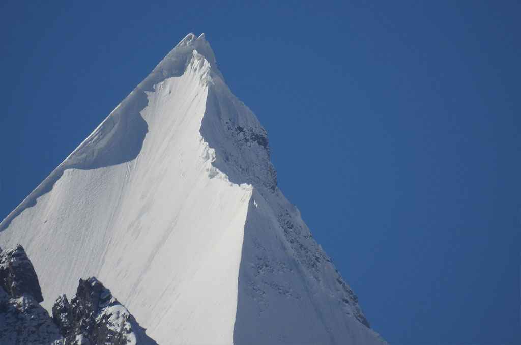 Summit pyramid of Humbroq Peak against a blue sky