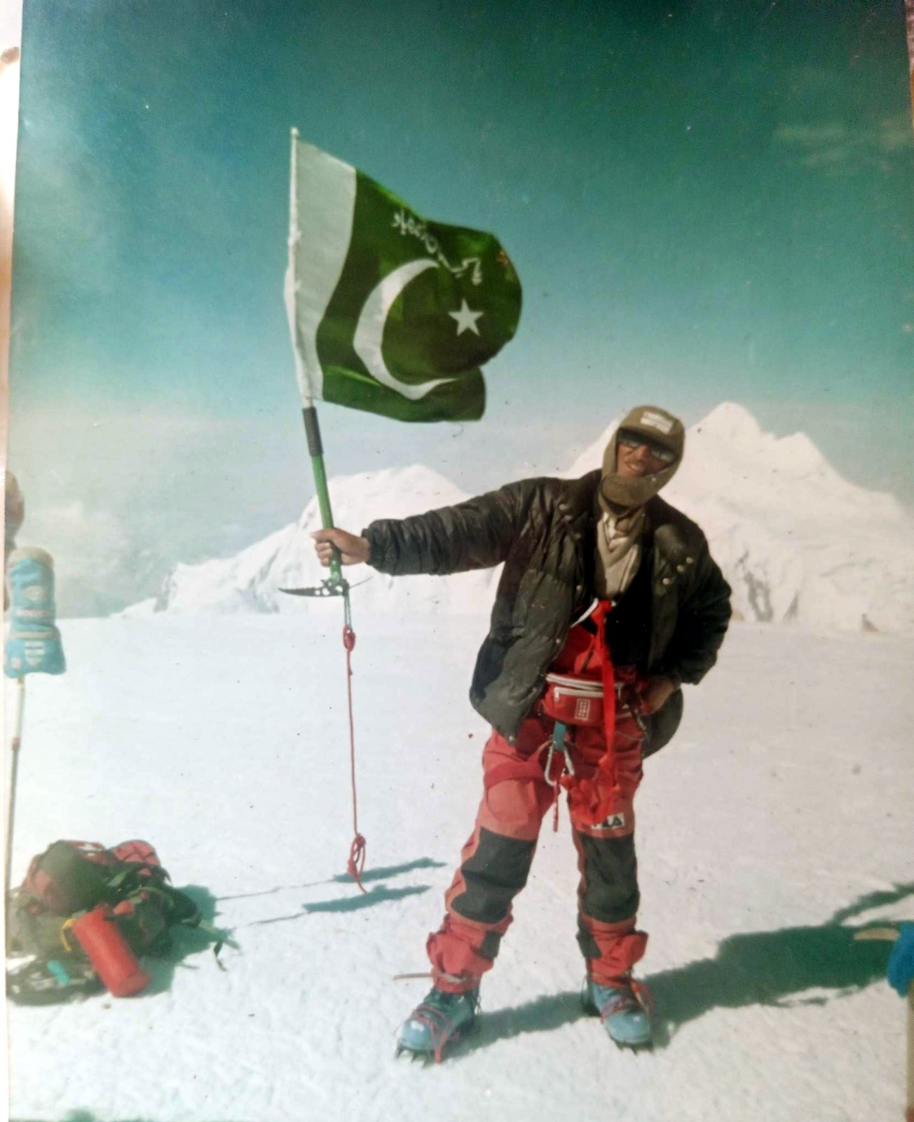 Rozi Ali on a Karakoram summit holding the flag of Pakistan
